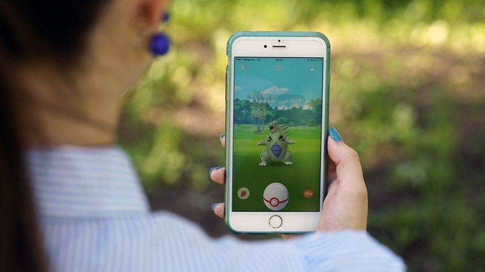 Person playing Pokemon Go game and has Tyranitar pokemon on screen.