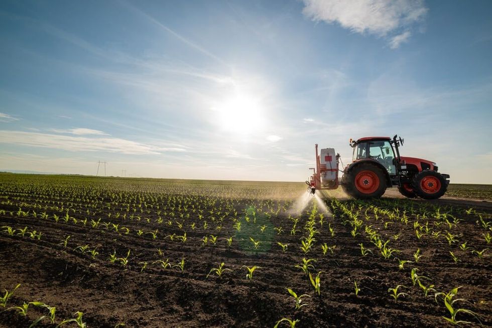 Photo of a tractor spraying fertilizers on a farm