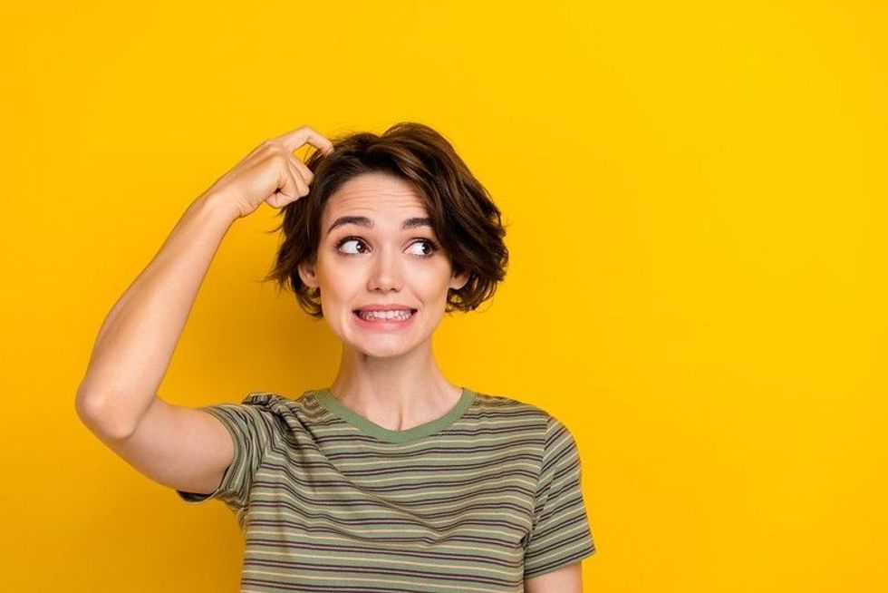 Photo of young pretty woman scratching head indicating an awkward moment