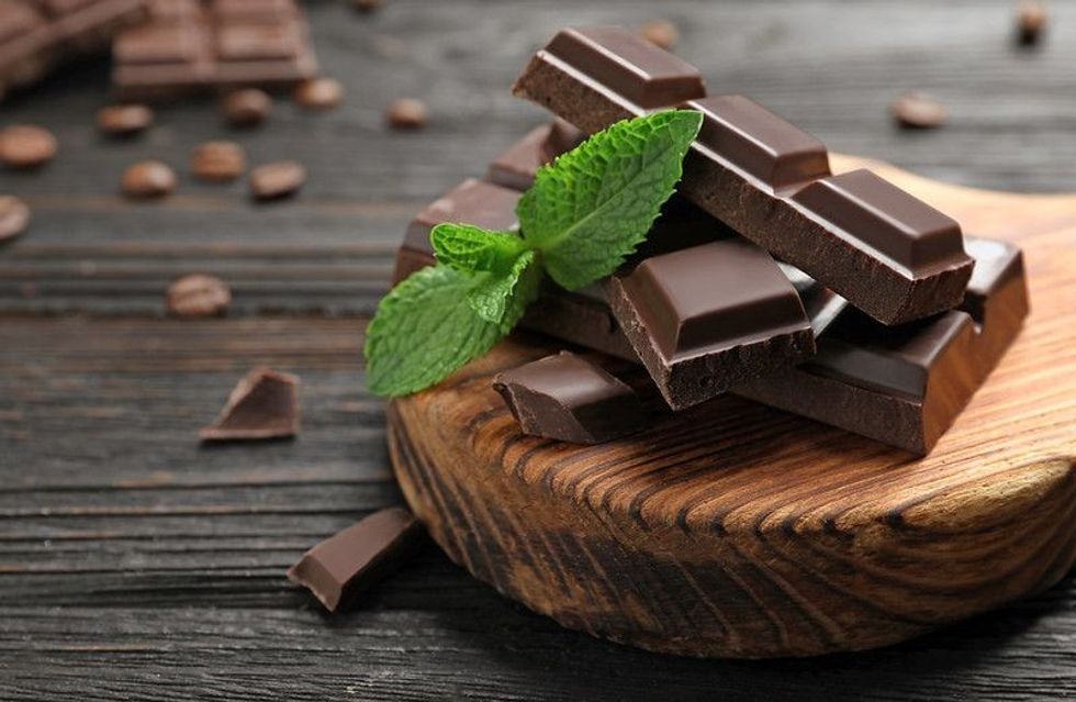 Pieces of dark chocolate with mint on wooden table