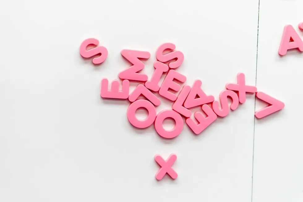 Pink alphabets scattered on white background