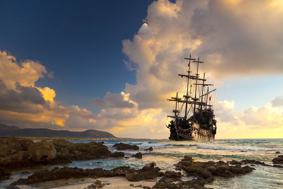 Pirate ship at the open sea at the sunset.