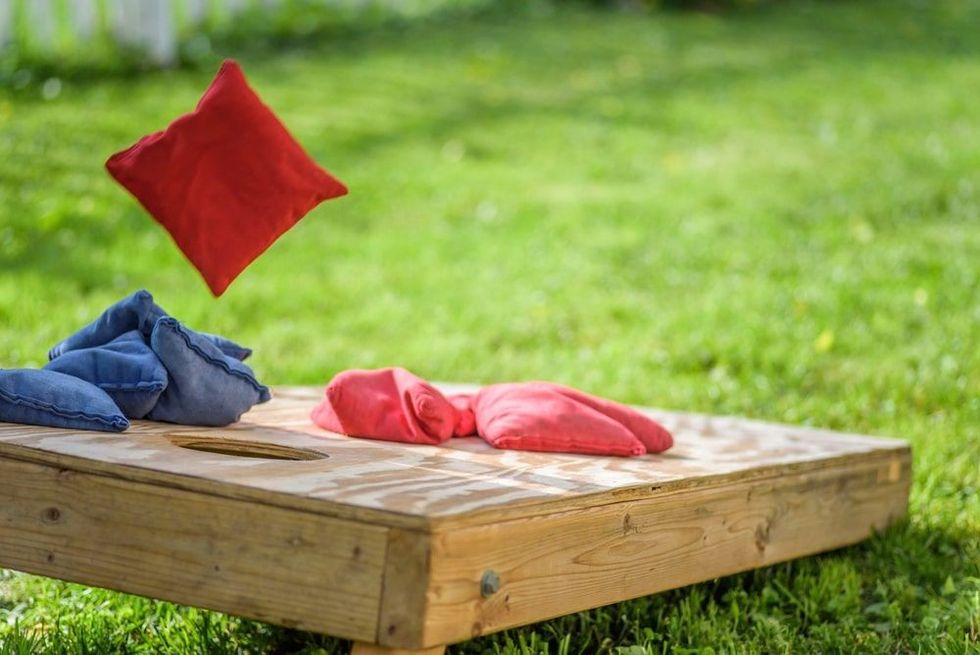 Playing cornhole in backyard throwing bag in air