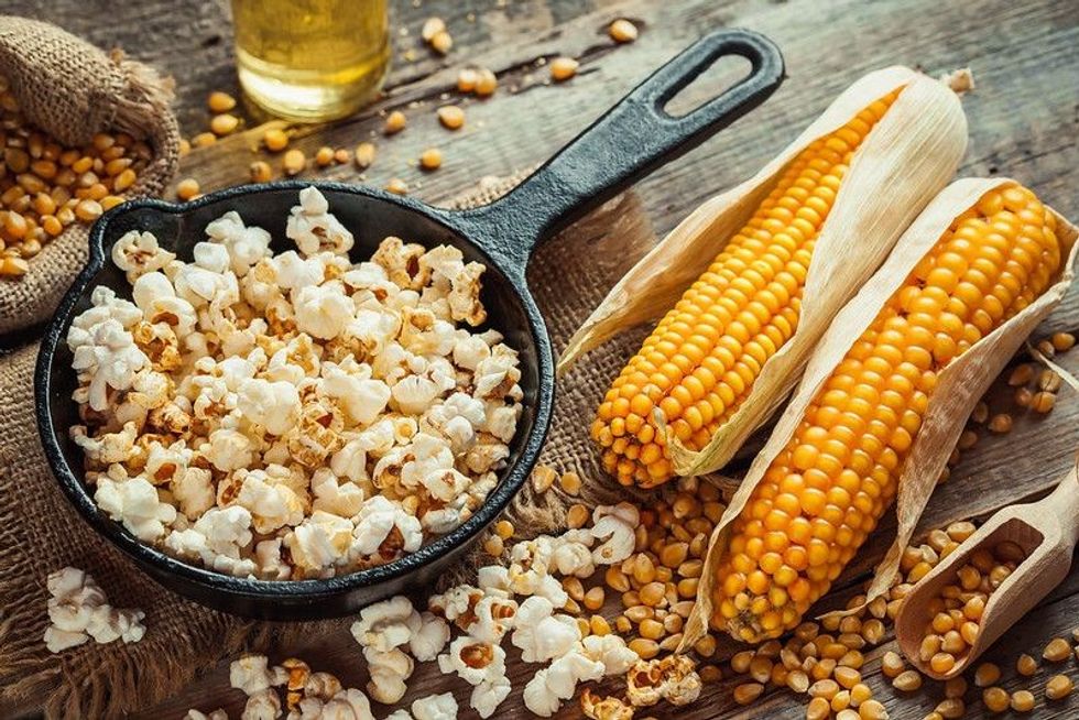 Popcorn in frying pan and corn seeds in bowl.