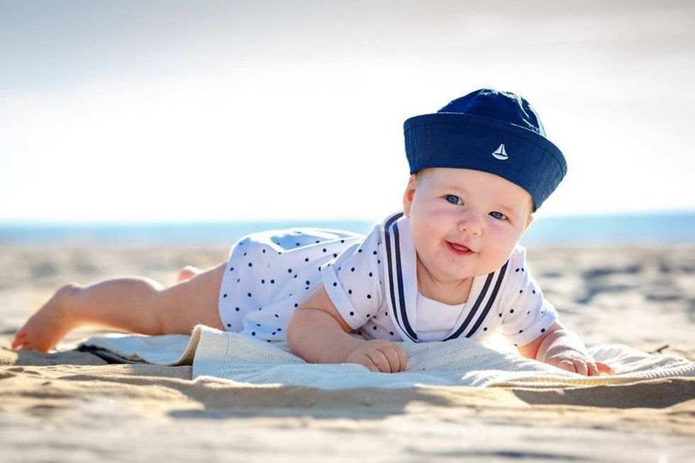 Portrait of a cute newborn baby lying on her stomach on tropical beach