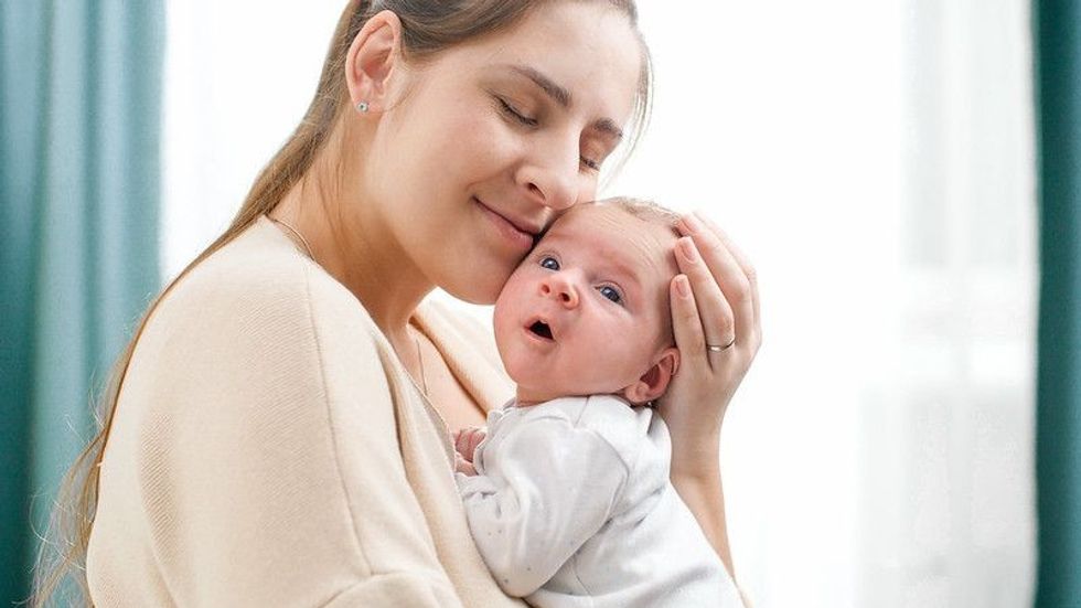 Portrait of happy smiling mother holding and looking her newborn baby