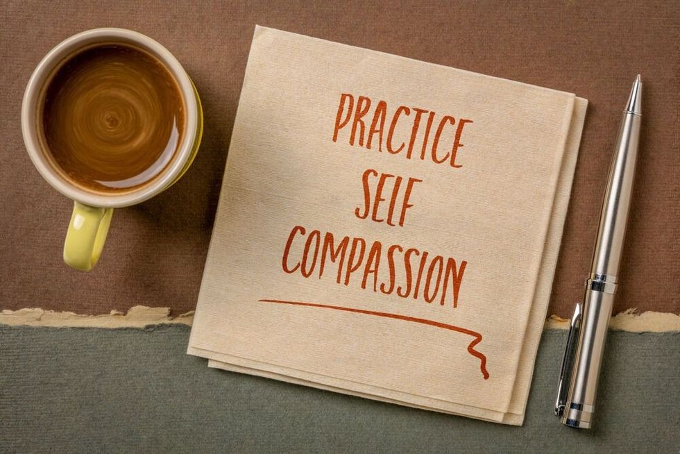 practice self-compassion inspirational handwriting on a napkin with coffee