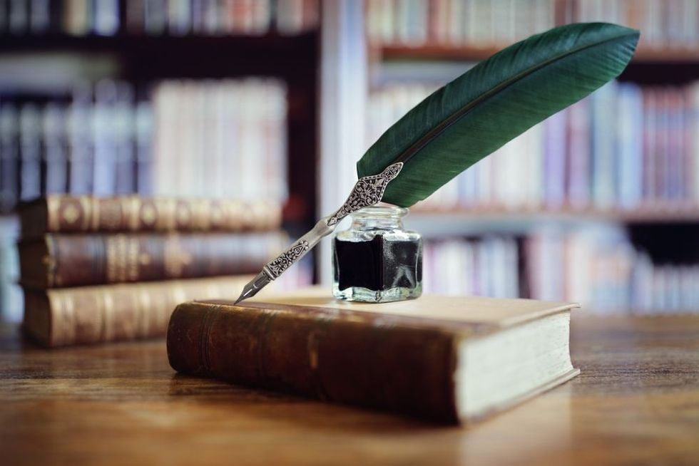 Quill pen and ink well resting on an old book