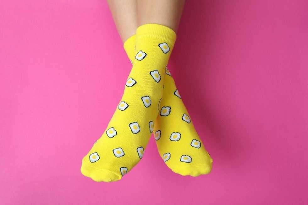 Quirky socks worn by a lady on a pink background