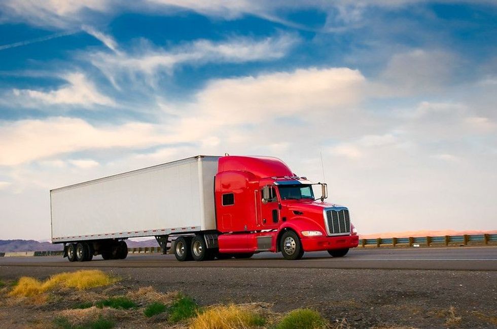 Red truck on road with cloudy background.