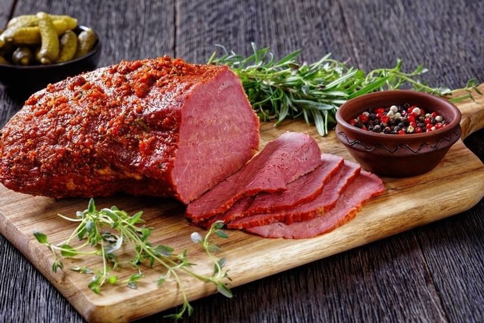 Roast beef pastrami on wooden board with fresh rosemary