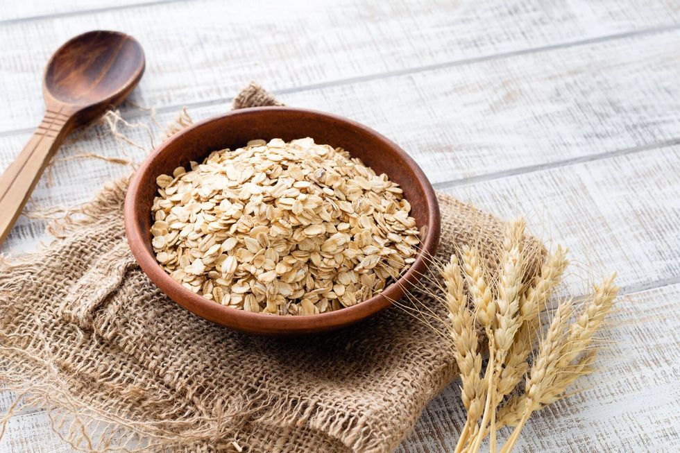 Rolled oats flakes in bowl on wooden table