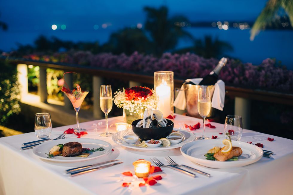 Romantic seaside candlelit dinner with gourmet dishes, champagne, and a stunning view.