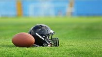Rugby helmet with ball on field