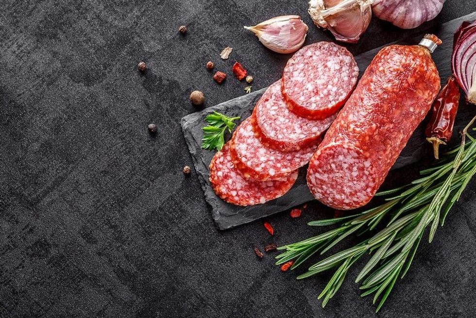 Salami sausage slices on a black chopping Board.