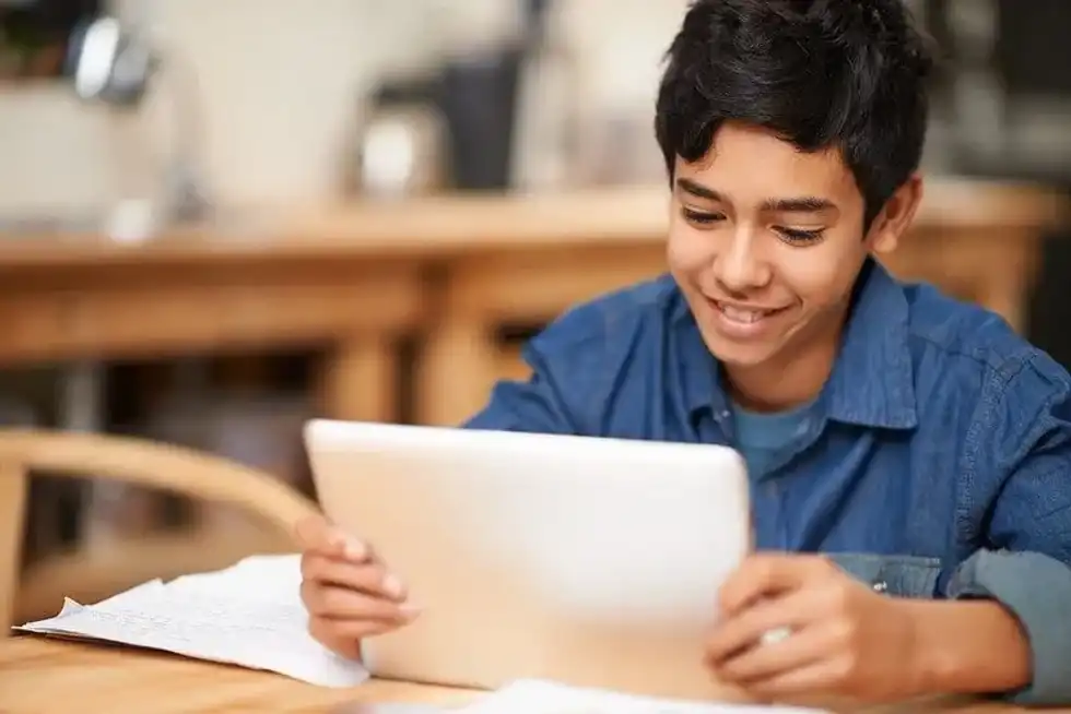 Schoolboy looking at a tablet to do his homework.