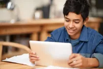 Schoolboy looking at a tablet to do his homework.