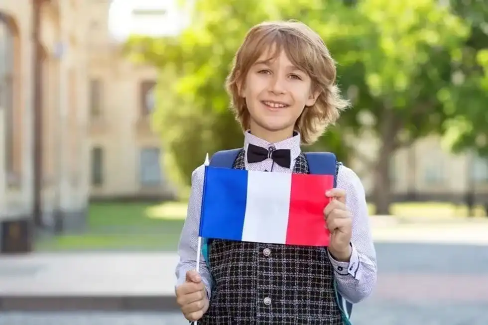 Schoolboy with the flag of France on the background of the school