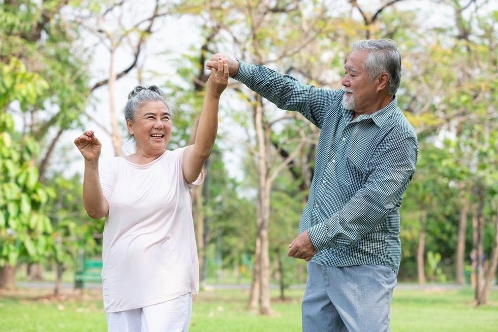 Senior happy couple dancing together in the park.