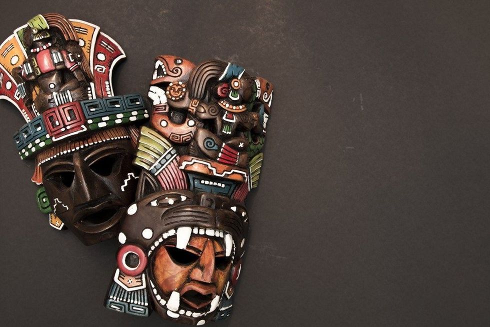 Set of two Mexican Mayan Aztec wood and ceramic mask on black background.