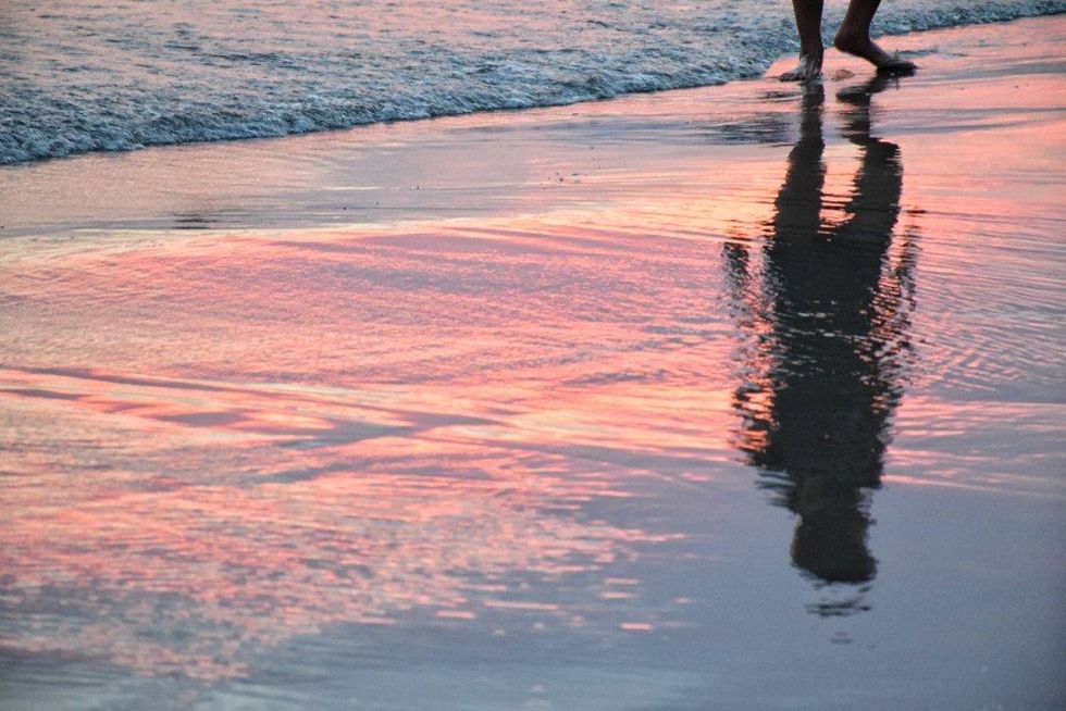 Shadow of man in beautiful light sunset at the shoreline.