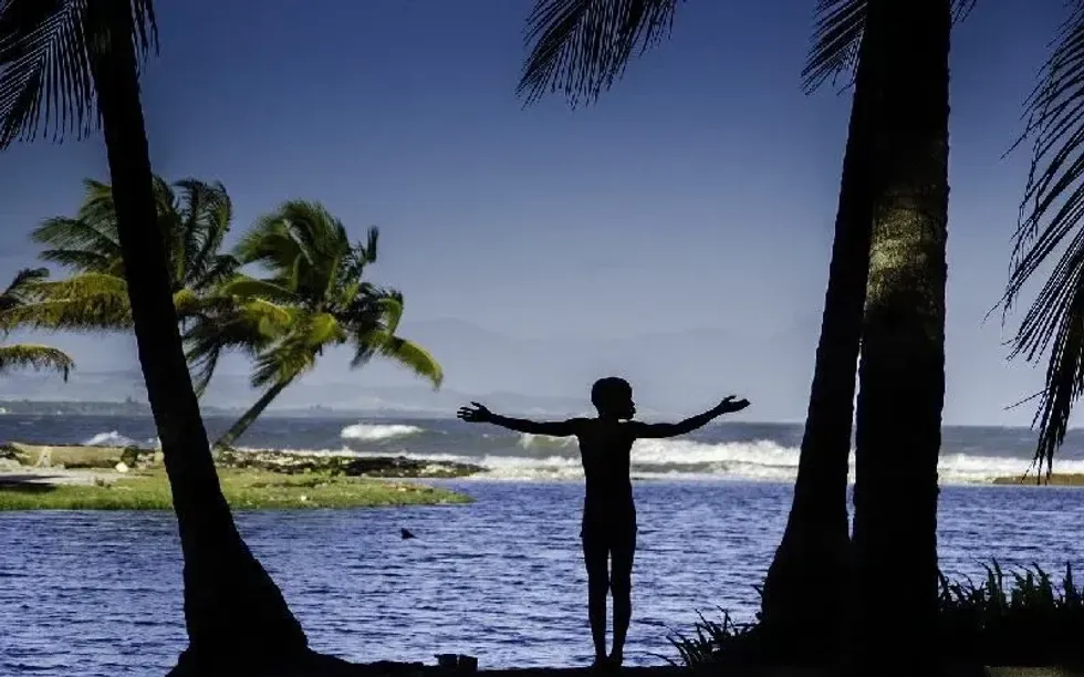 Silhouette of a young boy by the sea in Haiti.