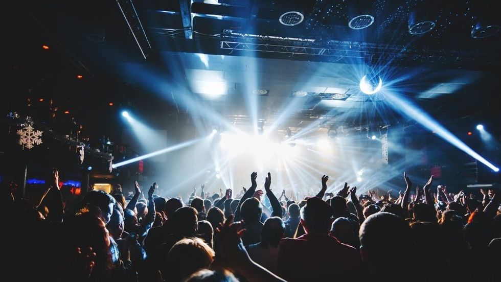 Silhouette of concert crowd in front of bright stage lights.