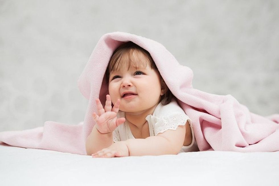 Six months old baby girl lying on blanket.
