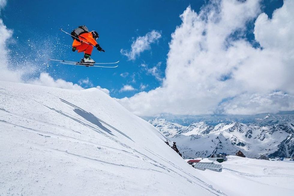 Skier midflight while ski jumping on the snowy mountain