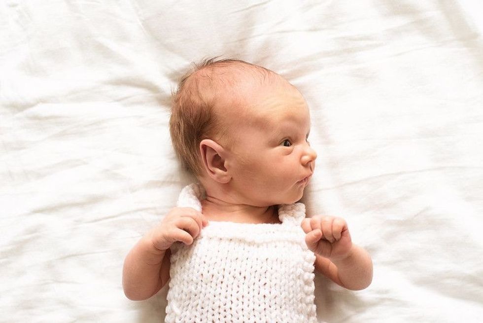 Small child lies on a white bed