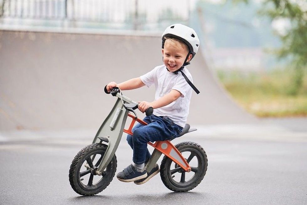 Smiling child riding balance bike.