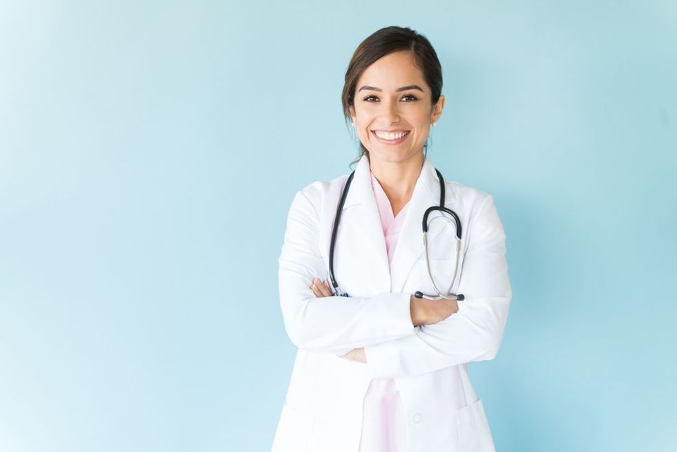 Smiling female doctor in lab coat with arms crossed