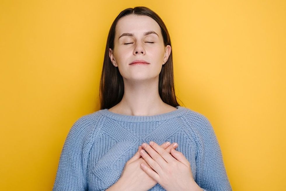 Smiling millennial young girl put folded palms on heart