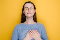 Smiling millennial young girl put folded palms on heart
