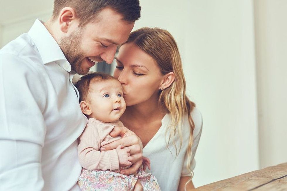 Smiling mother and father holding their newborn baby daughter