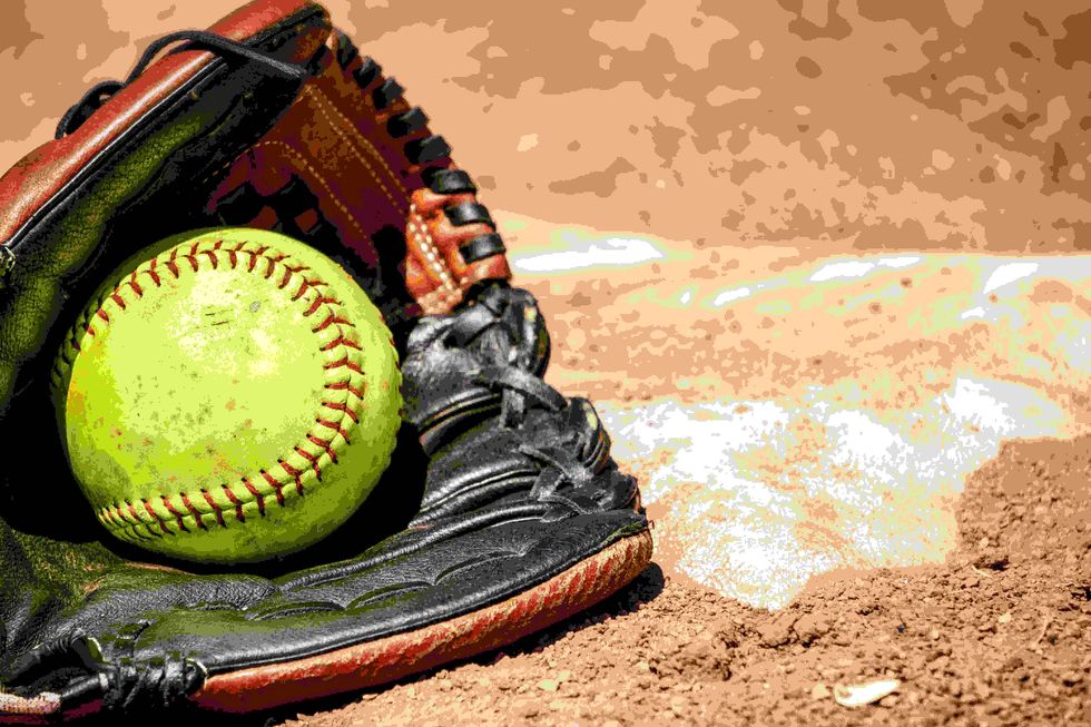 Softball and glove in front of the base.