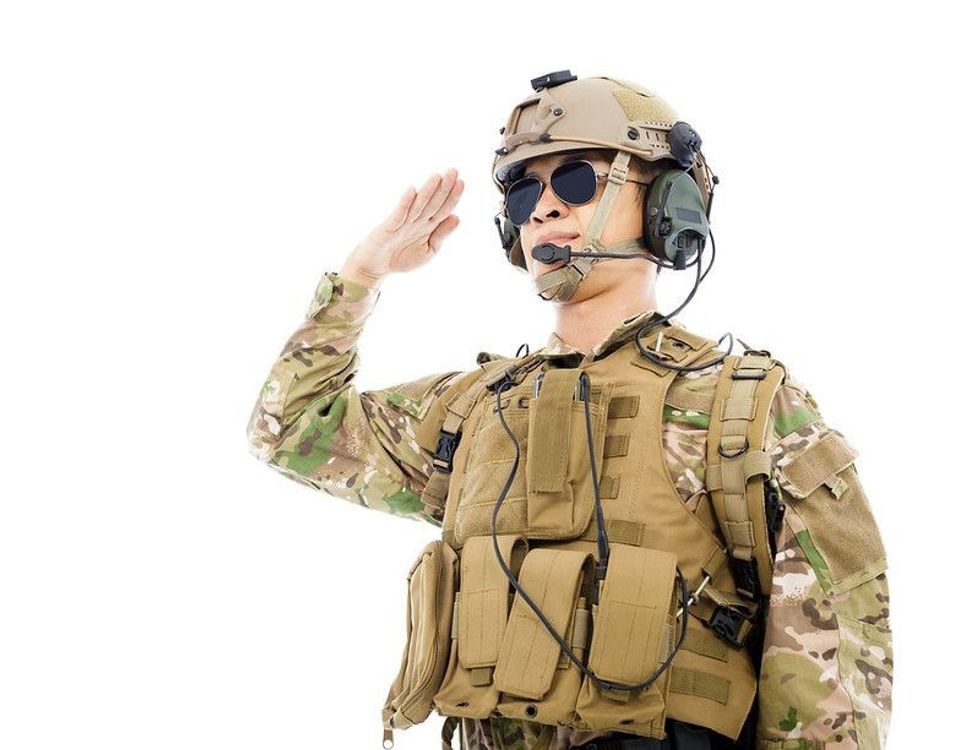 Soldier in military uniform saluting over white background