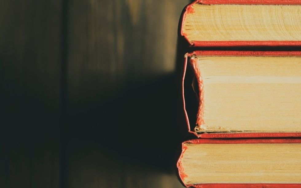 Spine of books with scarlet covers on a wooden background.