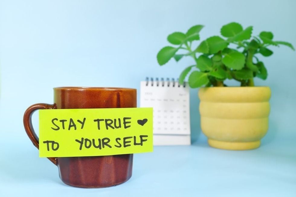 Stay true to yourself self message written on a paper note stuck to a coffee cup