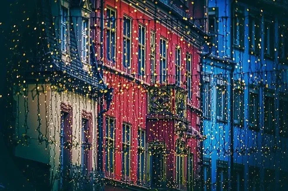 Street with colorful buildings adorned with festive string lights.