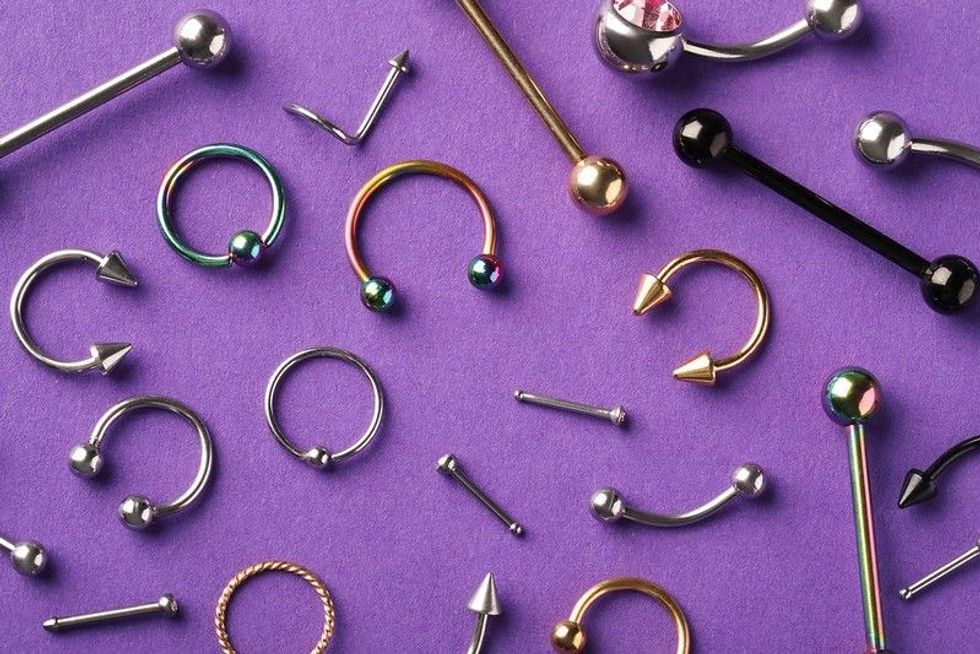 Stylish face piercing jewelry on violet background