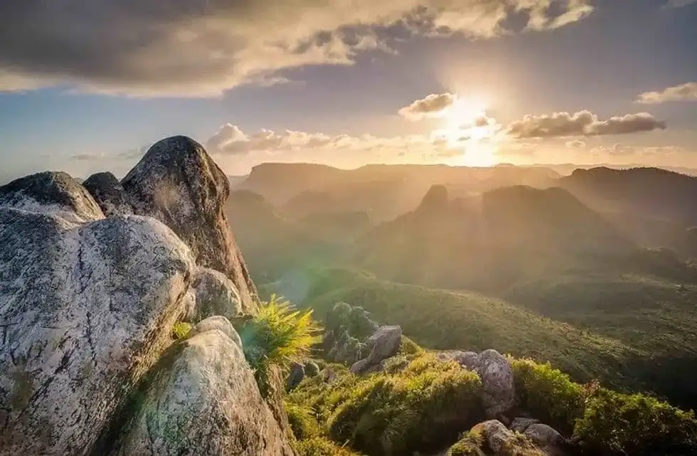 Sunrise over the countryside, rays of sunshine peeping over the hills.