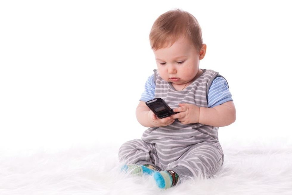 Sweet small baby with mobile phone on a white background.