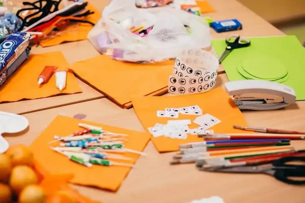 Table with paper and arts and crafts supplies on it to make origami bats.