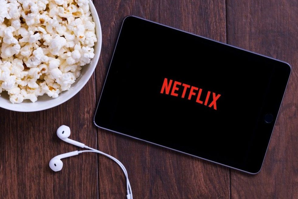 Table with popcorn bottle and Netflix logo on Apple Ipad mini and earphone. 