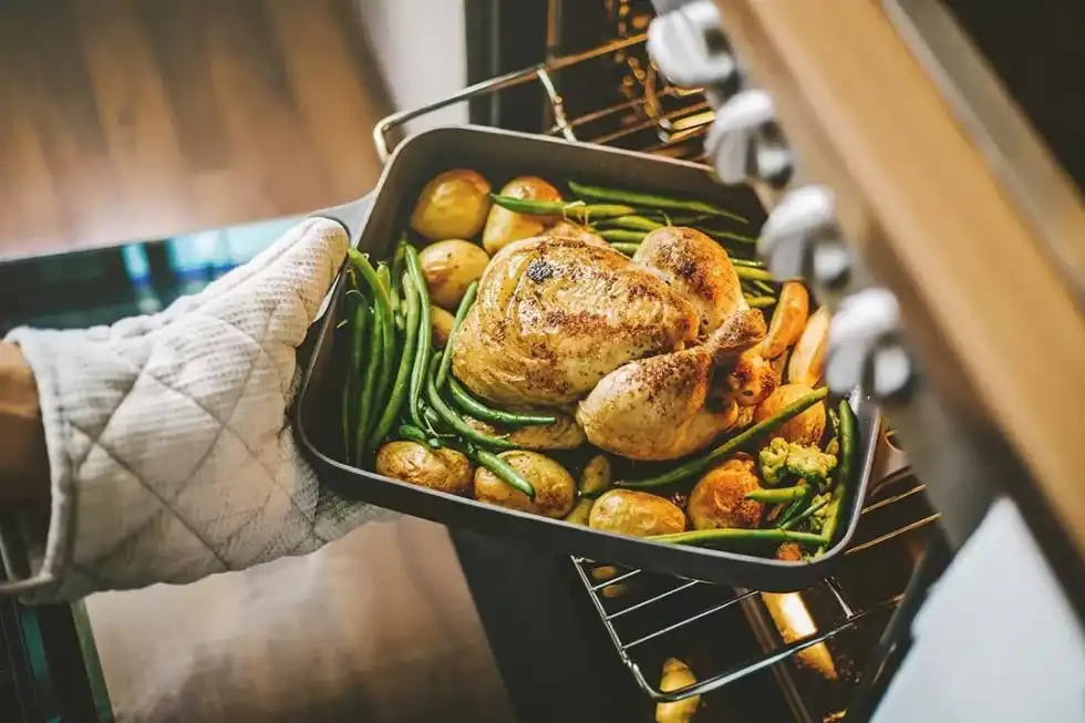 Taking out roast chicken from the oven for a Sunday lunch.