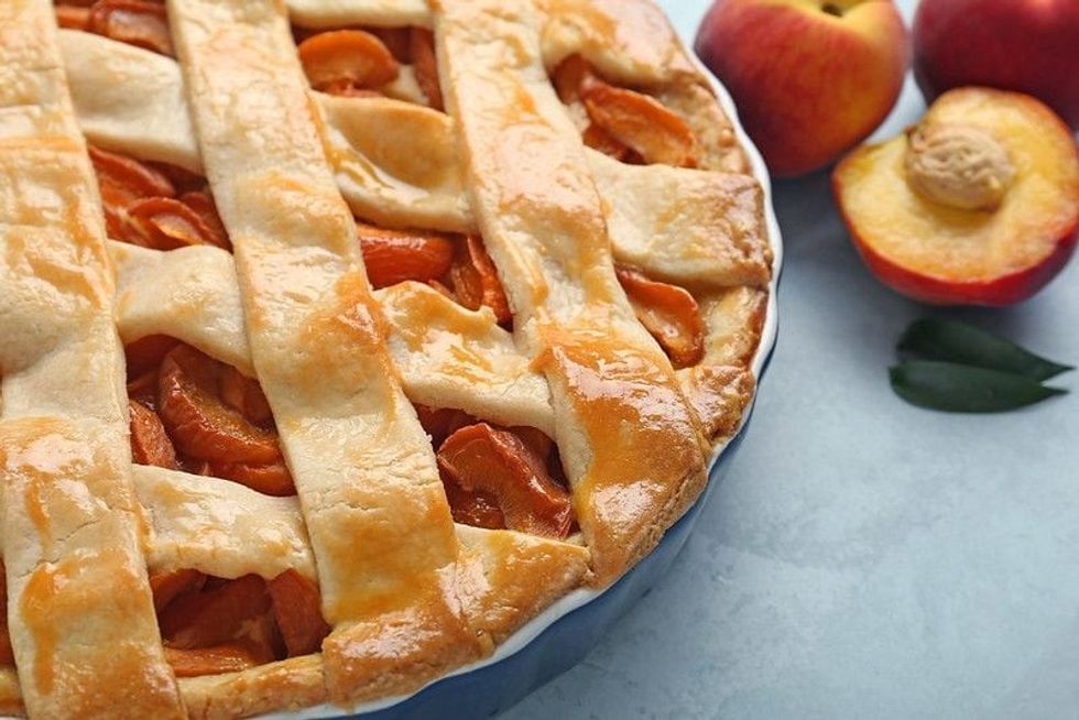 Tasty peach pie on table with peaches.