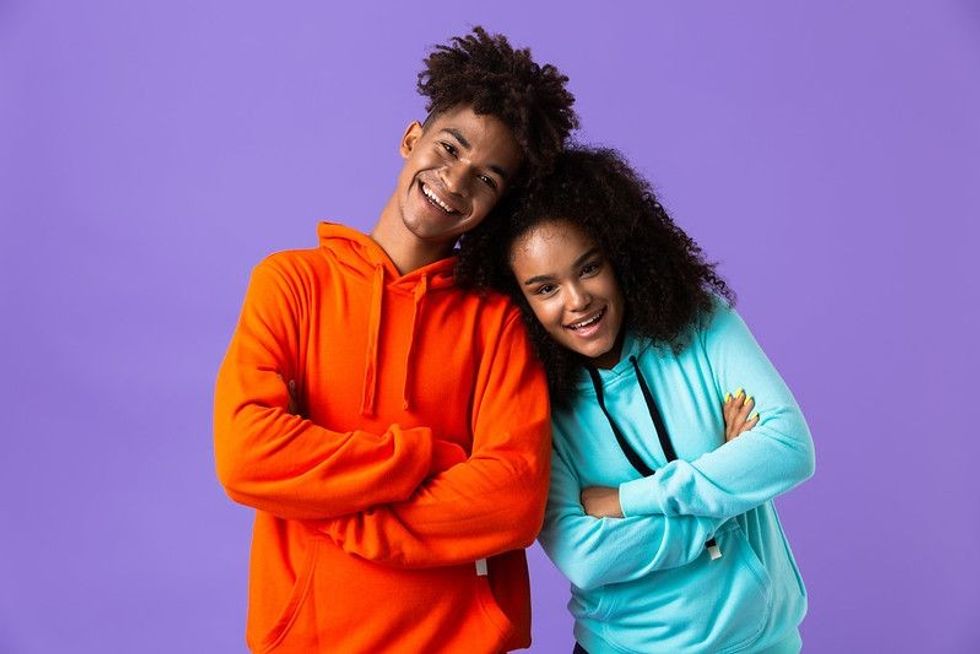 Teenage brother and sister standing in front of purple background