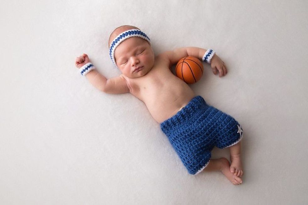 Ten day old newborn baby boy wearing basketball shorts and sweat bands