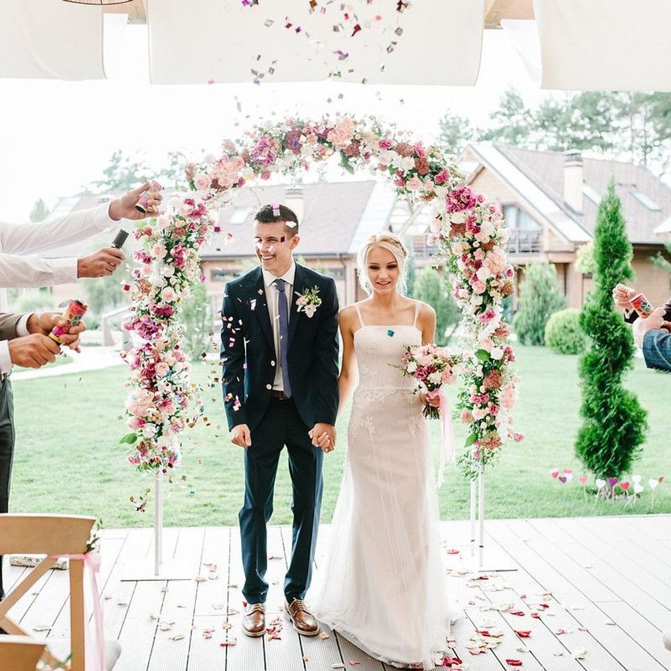The bride groom going through flowered arch 